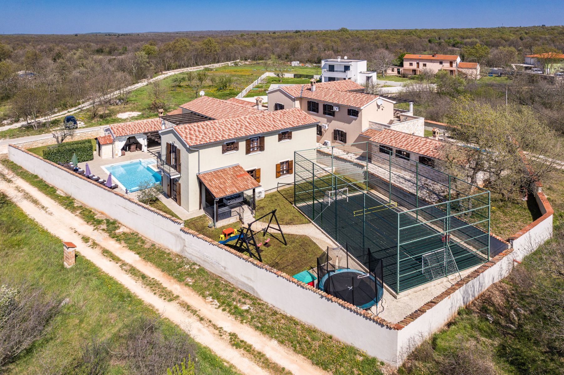 The walled garden with pool, playground, trampoline and sports court