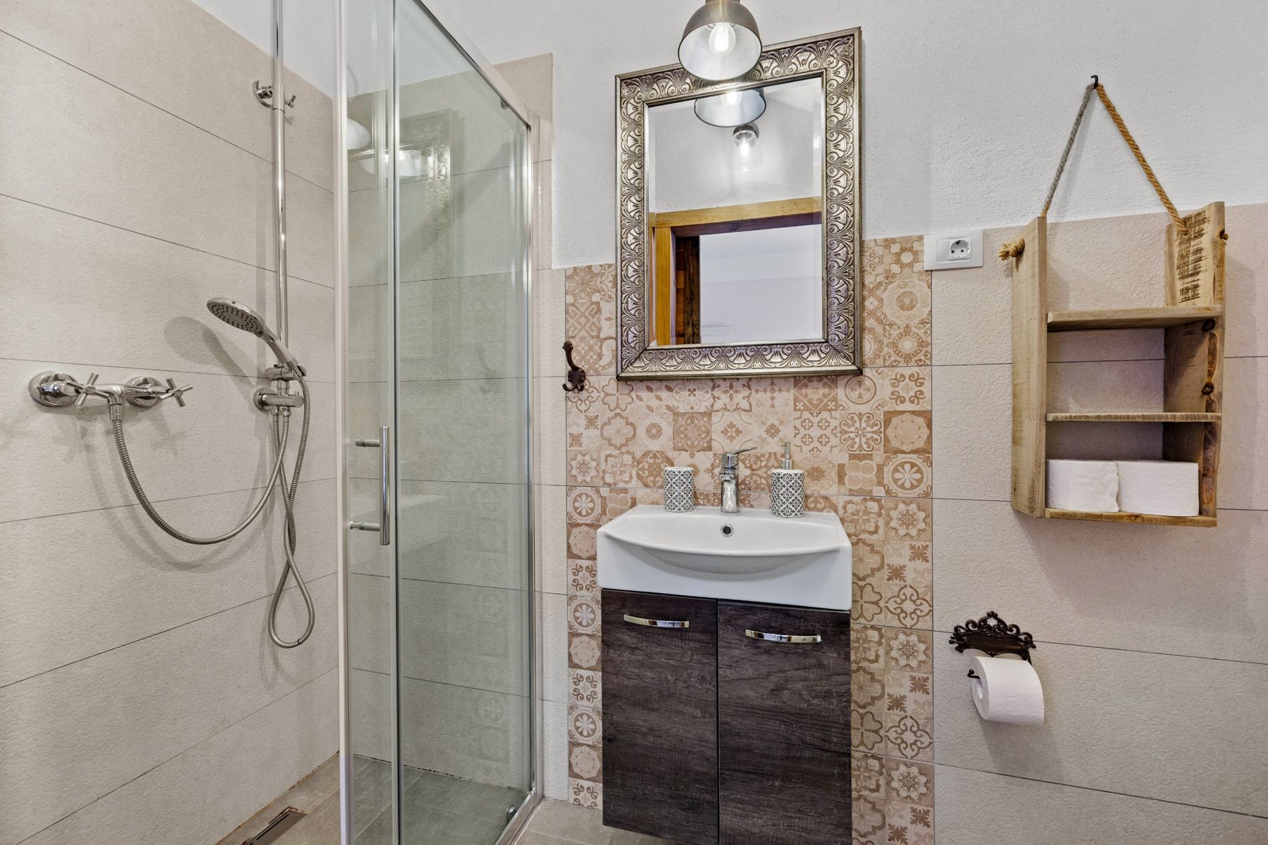 Bathroom with a glass shower, patterned tiles and a framed mirror