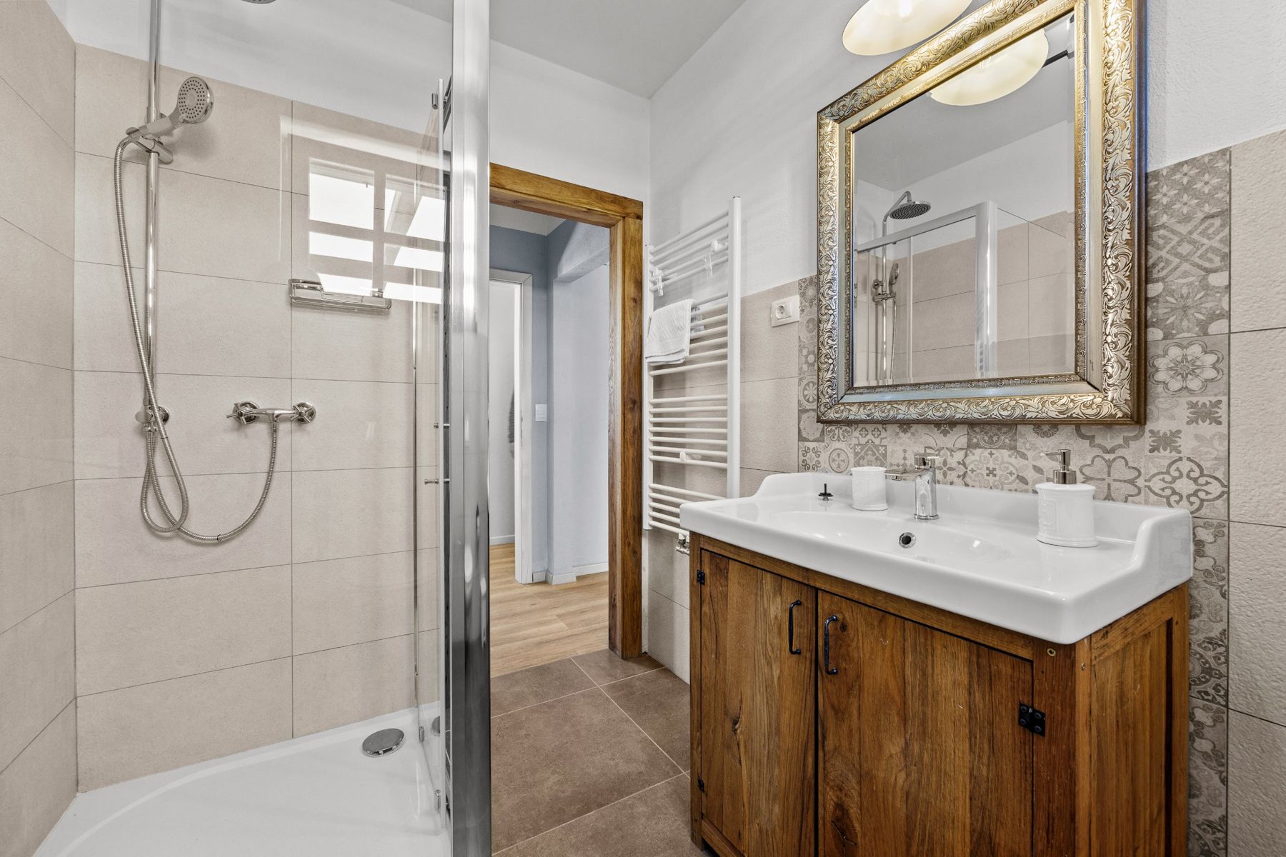 Bathroom with a corner shower, wooden vanity and heated towel rail