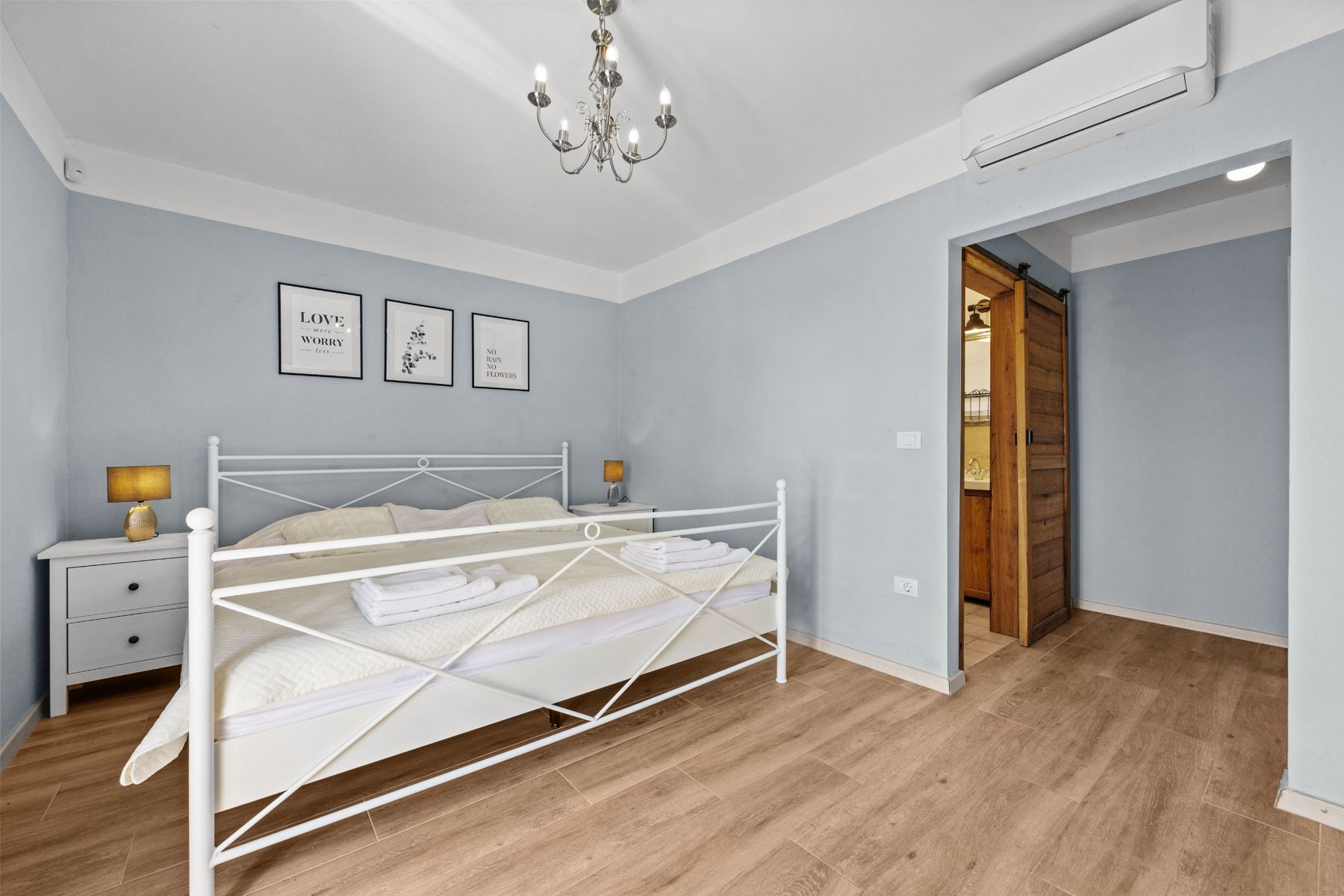 Light blue bedroom with a white metal bed and a sliding door to the bathroom