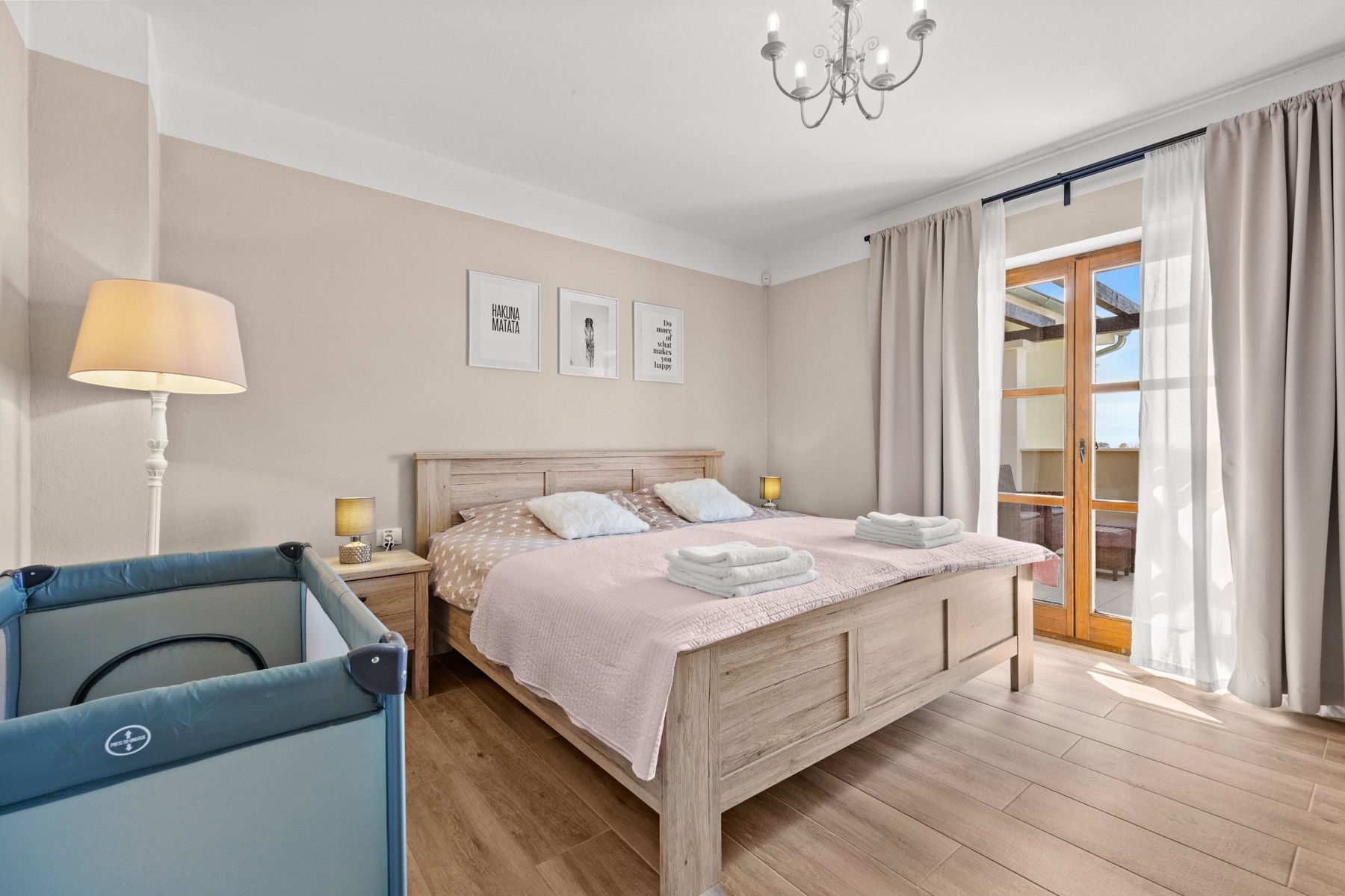 Bedroom with a wooden double bed, travel cot and door to the terrace