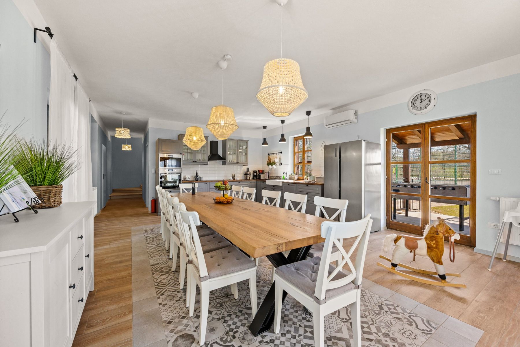 The long wooden dining table with white chairs, seen towards the kitchen