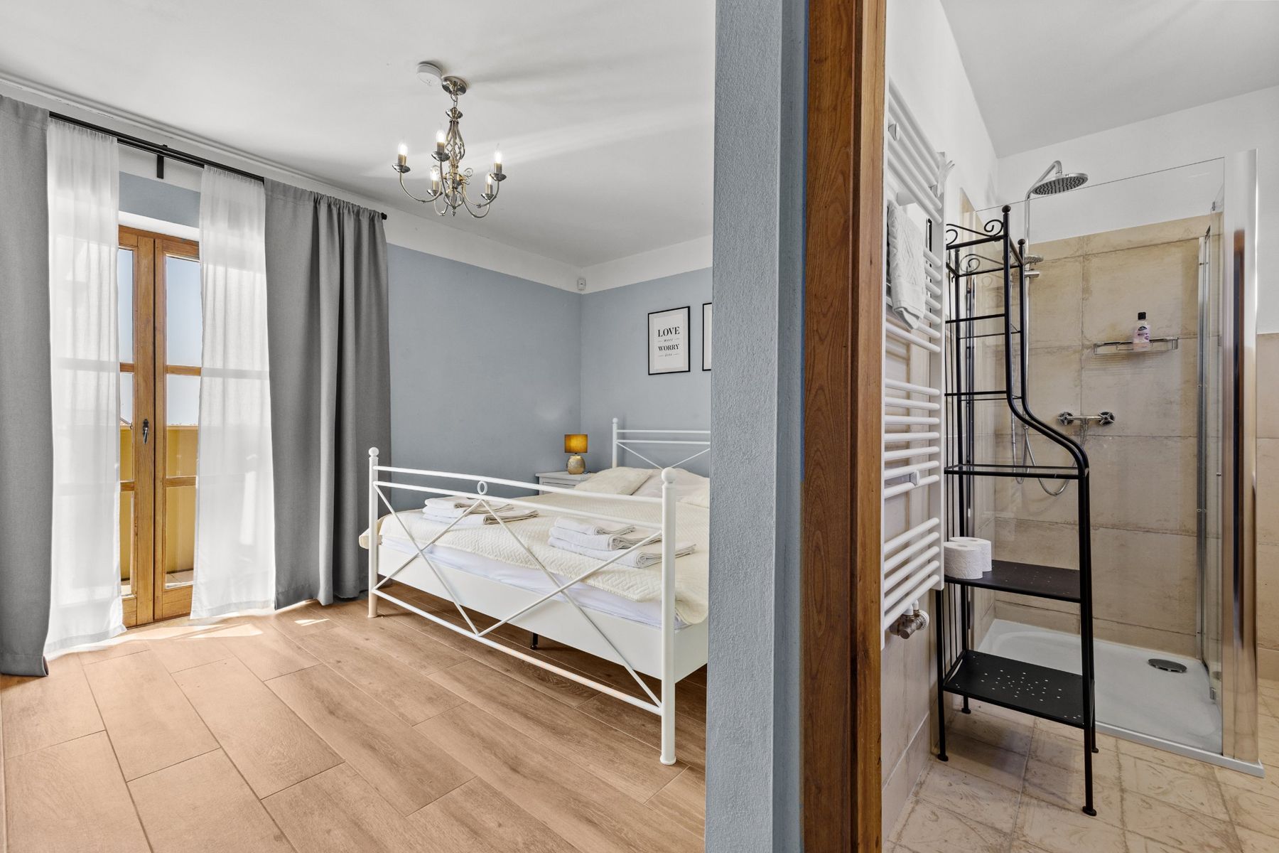 A blue bedroom with a balcony door, next to its ensuite shower room