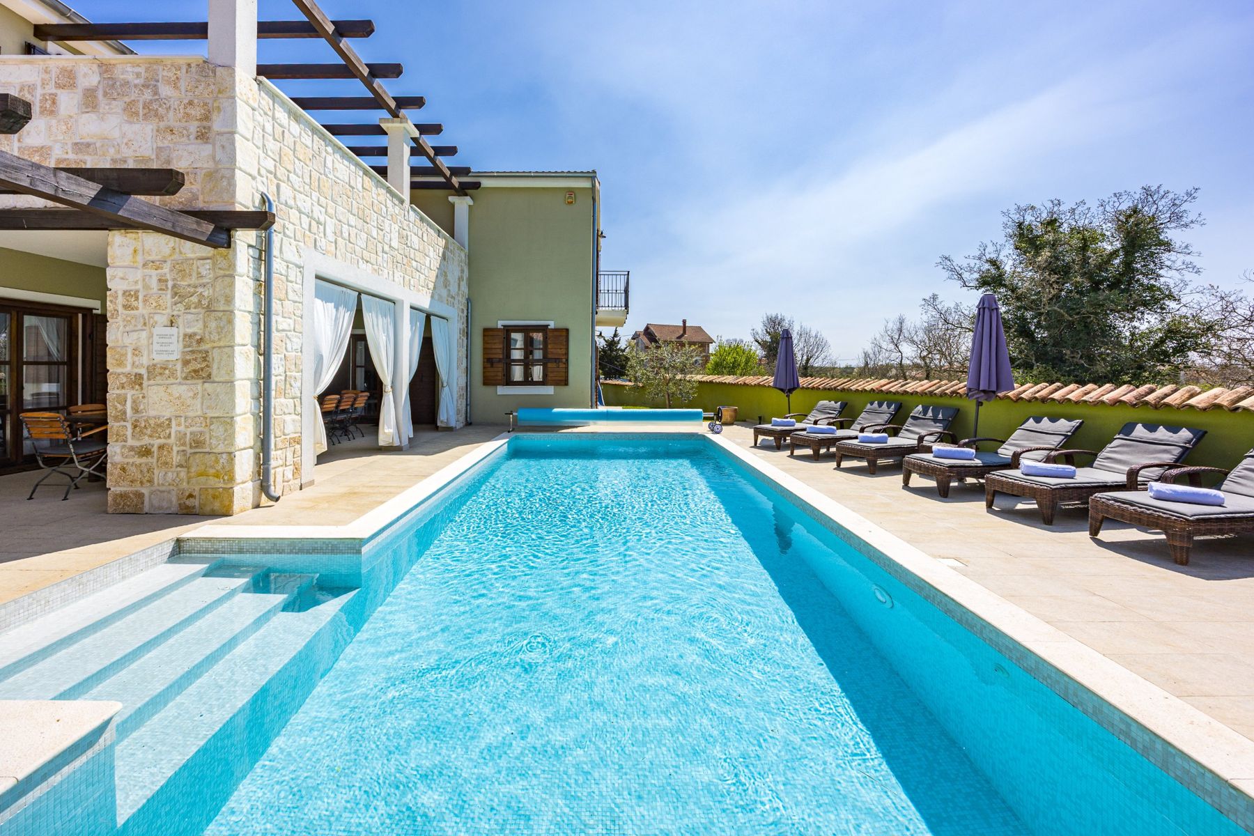 The pool with sun loungers and the covered dining terrace