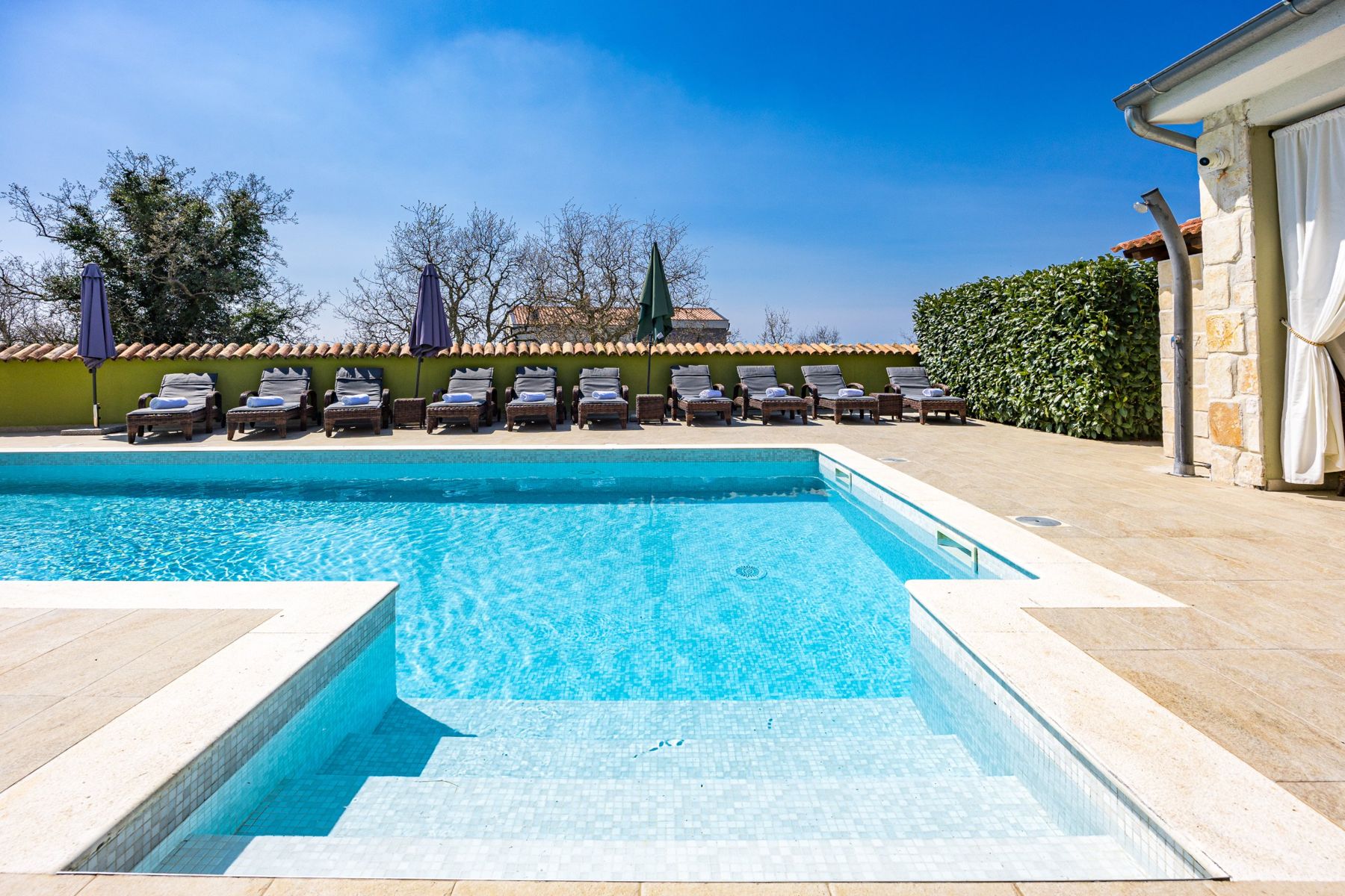 Pool steps and sun loungers along the garden wall